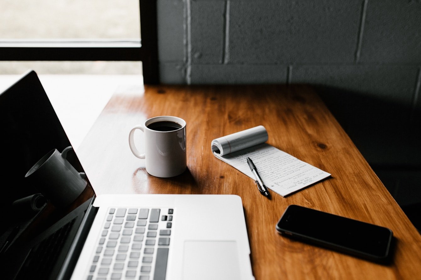 Minimal desk with laptop, notebook and coffee cup